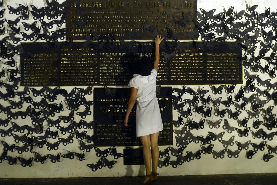 <p>A woman touches a memorial plate as she participates in a protest in commemoration of women murdered in El Salvador as part of the celebration of International Women’s Day in San Salvador on March 8, 2018. (Photo: Marvin Recinos/AFP/Getty Images) </p>