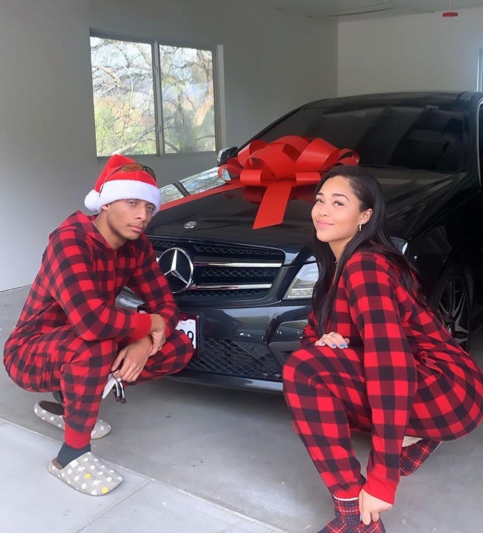 Jordyn Woods and brother pose by a car at Christmas
