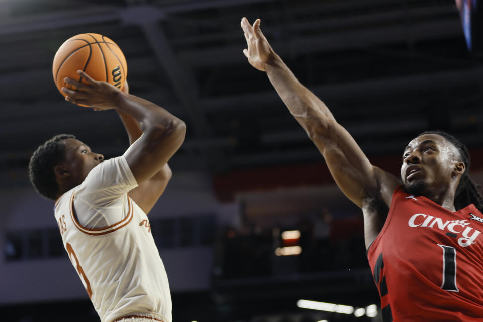 Texas' Max Abmas, left, shoots over Cincinnati's Day Day Thomas to score the winning basket during an NCAA college basketball game Tuesday, Jan. 9, 2024, in Cincinnati. (AP Photo/Jay LaPrete)