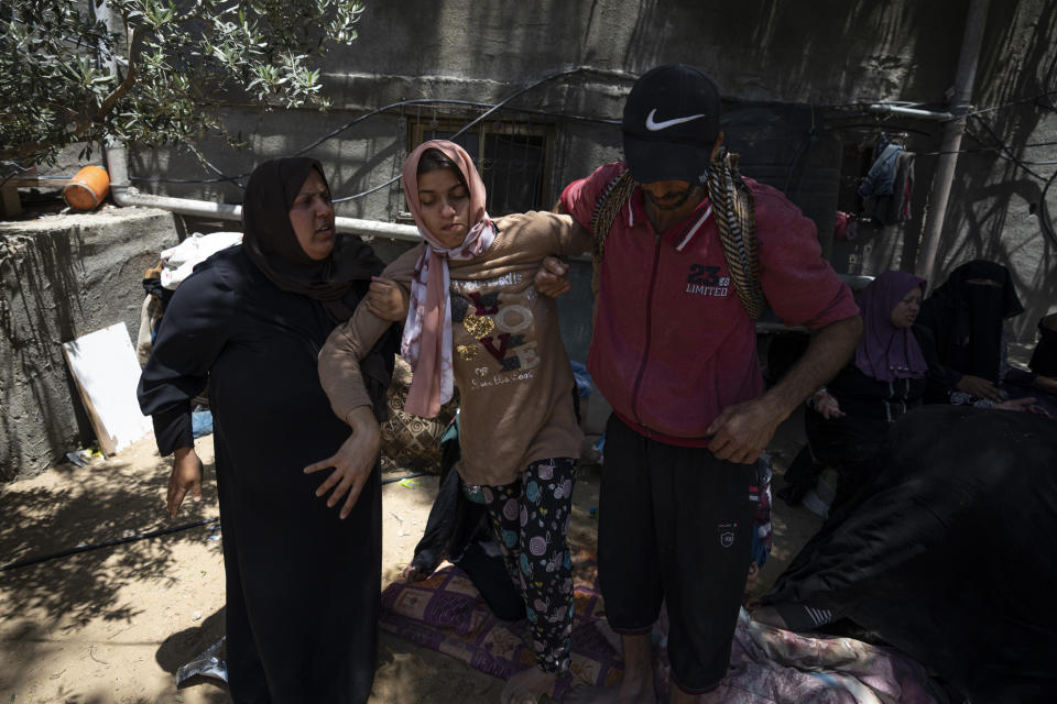 Relatives help Haneen Nabhan, who is physically disabled, next to the ruins of her family's home, which was destroyed in an Israeli airstrike, in Jabaliya, northern Gaza Strip, Sunday, May 14, 2023. The airstrike left 42 members of the extended family homeless. It also left four children with special needs without their wheelchairs, crutches and medical equipment needed to move about. Israel says the building was used as a command center by the Islamic Jihad militant group. The two sides reached a cease-fire Saturday to end five days of fighting. (AP Photo/Fatima Shbair)