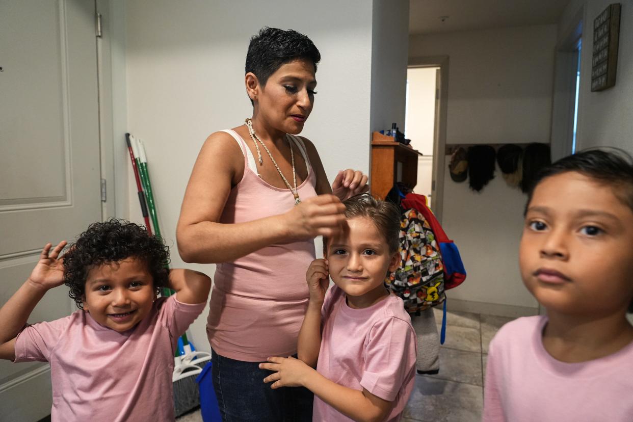 Kristin Ramirez fixes son Matthew Ximenez's hair. Ramirez has advanced breast cancer and is undergoing chemotherapy while taking care of her six children as a single parent.