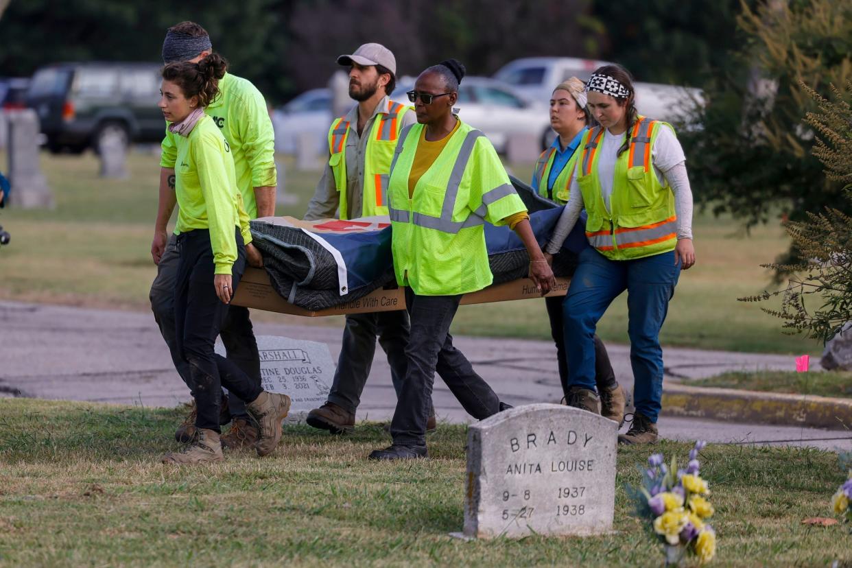 Researchers and burial oversight committee member Brenda Alford carry the first set of remains exhumed from the latest dig site in Oaklawn Cemetery to an onsite lab for further examination in Tulsa