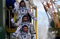 Kazakhstan's cosmonaut Aydyn Aimbetov (C), Russian cosmonaut Sergei Volkov and Denmark's astronaut Andreas Mogensen from the European Space Agency (top) wave as they board the Soyuz TMA-18M spacecraft at the Russian-leased Baikonur cosmodrome early September 2, 2015. REUTERS/Kirill Kudryavtsev/Pool