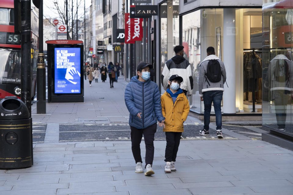 People wearing face masks walk along the shopping district Oxford Street which is largely empty of shoppers as the national coronavirus lockdown three continues on 28th January 2021 in London, United Kingdom. Following the surge in cases over the Winter including a new UK variant of Covid-19, this nationwide lockdown advises all citizens to follow the message to stay at home, protect the NHS and save lives. (photo by Mike Kemp/In Pictures via Getty Images)