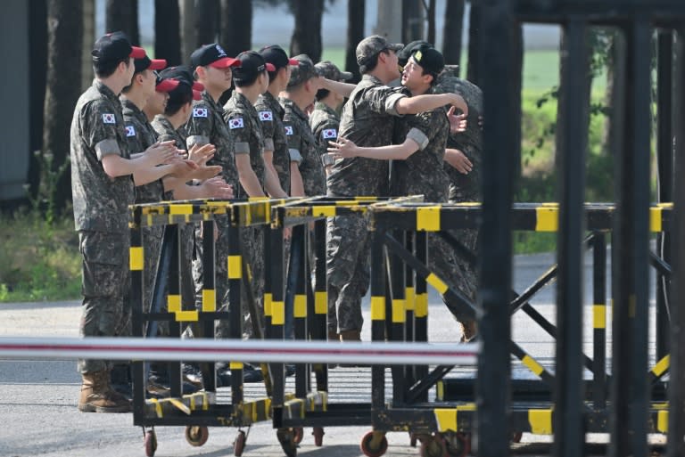 El miembro de la banda de K-pop BTS Jin (drcha.) abraza a sus compañeros al terminar el servicio militar, el 12 de junio de 2024 en la base de Yeoncheon, en Corea del Sur (Jung Yeon-je)