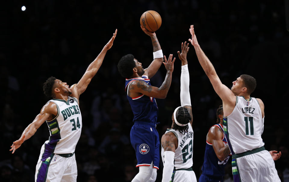 Brooklyn Nets guard Kyrie Irving (11) shoots from between Milwaukee Bucks' Giannis Antetokounmpo (34), Wesley Matthews (23) and Brook Lopez (11) during the first half of an NBA basketball game Thursday, March 31, 2022, in New York. (AP Photo/Noah K. Murray)