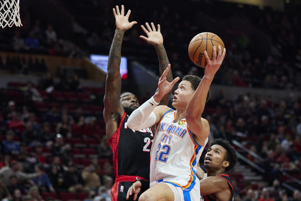 Oklahoma City Thunder forward Isaiah Roby, center, shoots over Portland Trail Blazers forward Keljin Blevins, left, during the second half of an NBA basketball game in Portland, Ore., Monday, March 28, 2022. (AP Photo/Craig Mitchelldyer)