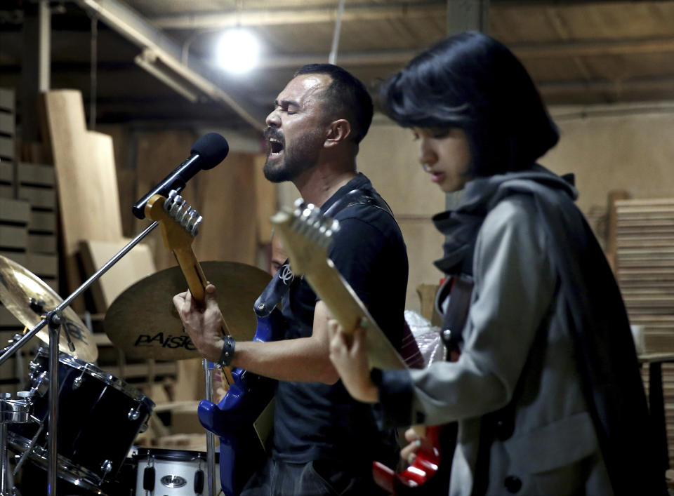In this July 20, 2018 photo, members of the rock band Arikayn, Afghan musicians Hakim Ebrahimi, center, and Soraya Hosseini, play at a furniture workshop in Eslamshahr, on the outskirts of Iran’s capital, Tehran. The band, made up of Afghan migrants, plays Metallica-inspired ballads about the struggles of millions of Afghans who have fled to Iran to escape decades of war and unrest. In Iran they face discrimination, and have had to contend with hard-liners opposed to Western culture. (AP Photo/Ebrahim Noroozi)