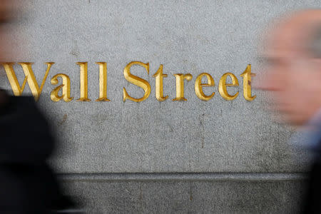 People walk by a Wall Street sign close to the New York Stock Exchange (NYSE) in New York, U.S., April 2, 2018. REUTERS/Shannon Stapleton