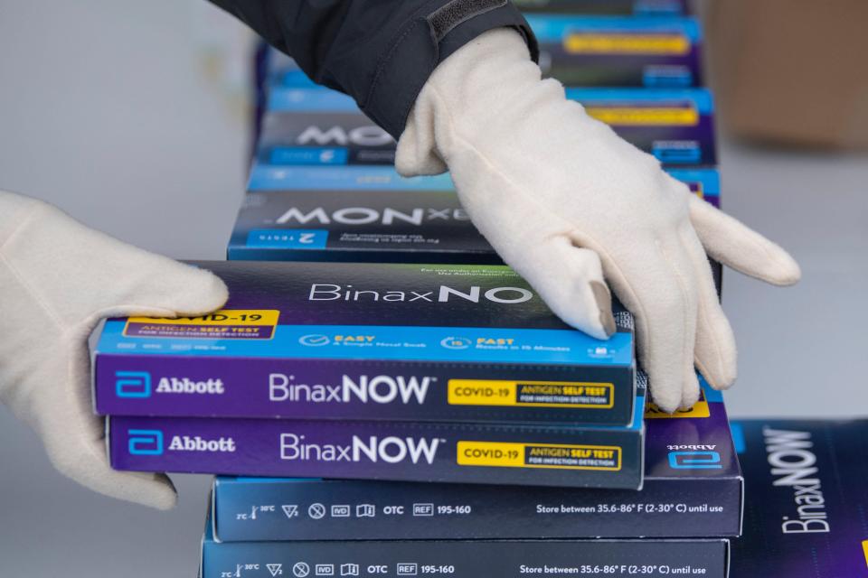 Youngstown City Health Department worker Faith Terreri grabs two at-home COVID-19 test kits to be handed out during a distribution event, Dec. 30, 2021, in Youngstown, Ohio. Private health insurers are required to cover up to eight home COVID-19 tests per month for those on their plans.