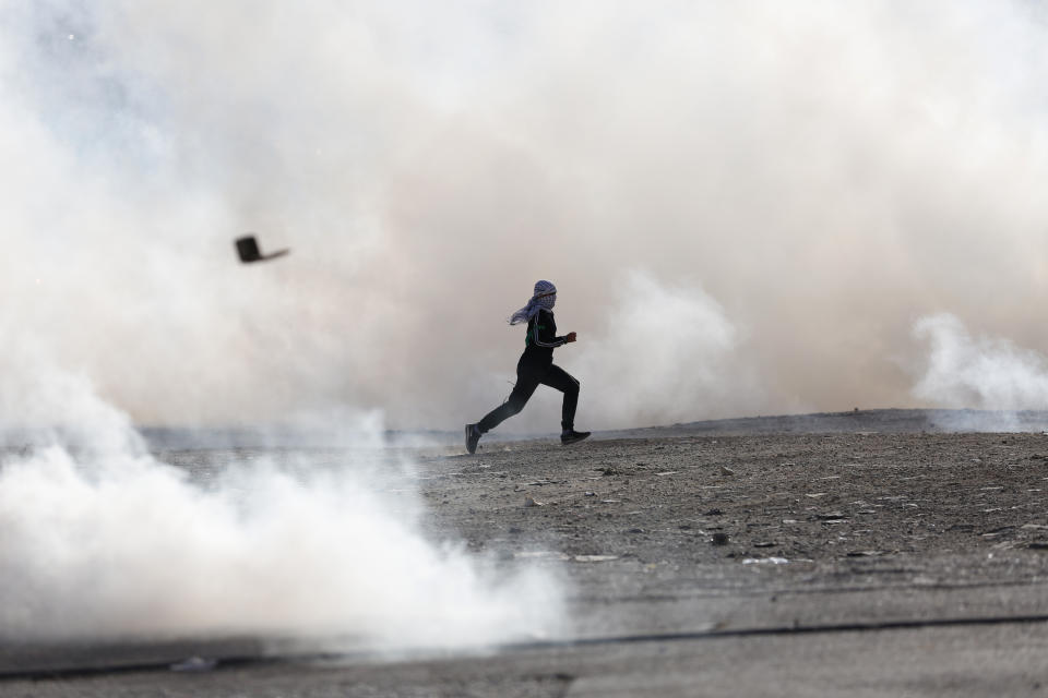 Palestinian demonstrators run from tear gas fired by Israeli troops during the protest against the U.S. announcement that it no longer believes Israeli settlements violate international law., at checkpoint Beit El near the West Bank city of Ramallah, Tuesday, Nov. 26, 2019, (AP Photo/Majdi Mohammed)