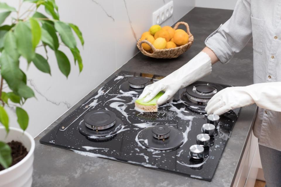 Person scrubbing stove burners with sponge.