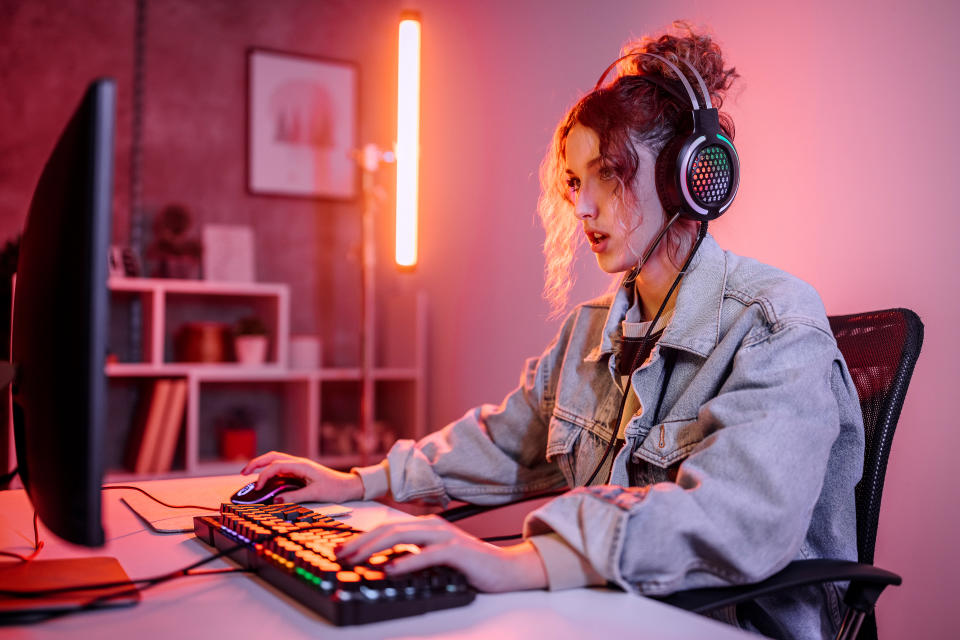 Young woman live streaming while playing multiplayer online game in living room at home