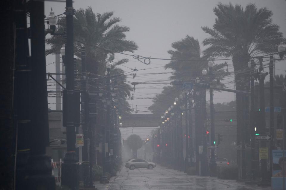 A vehicle drives through rain and high winds across Canal Street in New Orleans, Louisiana on August 29, 2021 during Hurricane Ida.