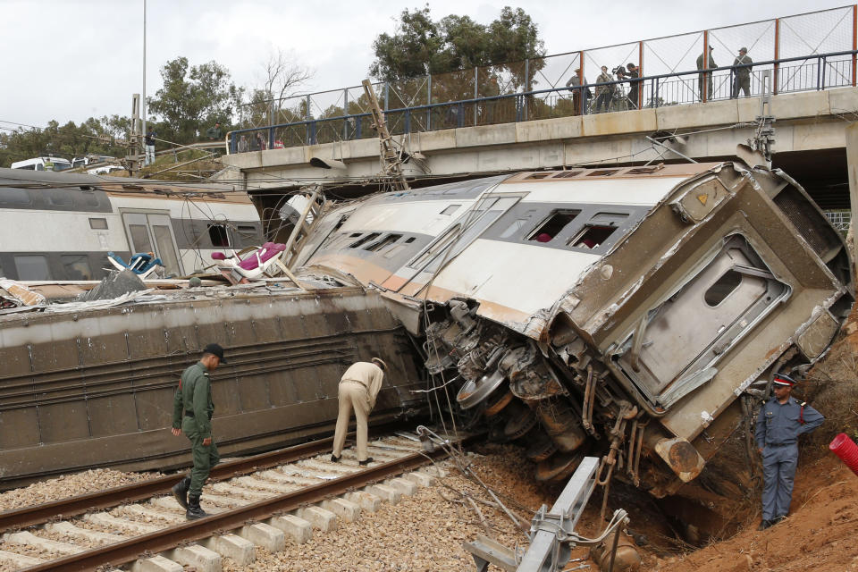 Un elemento de la policía y trabajadores ferroviarios revisan un tren que se descarriló el martes 16 de octubre de 2018 cerca de la localidad de Sidi Bouknadel, en Marruecos. (AP Foto/Abdeljalil Bounhar)