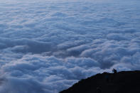 A climber stops to take pictures of clouds while climbing towards the summit of Mount Fuji to watch the sunrise, Tuesday, Aug. 27, 2019, in Japan. (AP Photo/Jae C. Hong)