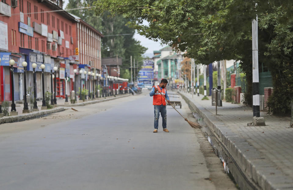 A civic worker cleans a deserted street during a security lockdown in Srinagar, Indian controlled Kashmir, Monday, Aug. 12, 2019. Troops in India-administered Kashmir allowed some Muslims to walk to local mosques alone or in pairs to pray for the Eid al-Adha festival on Monday during an unprecedented security lockdown that still forced most people in the disputed region to stay indoors on the Islamic holy day. (AP Photo/Mukhtar Khan)