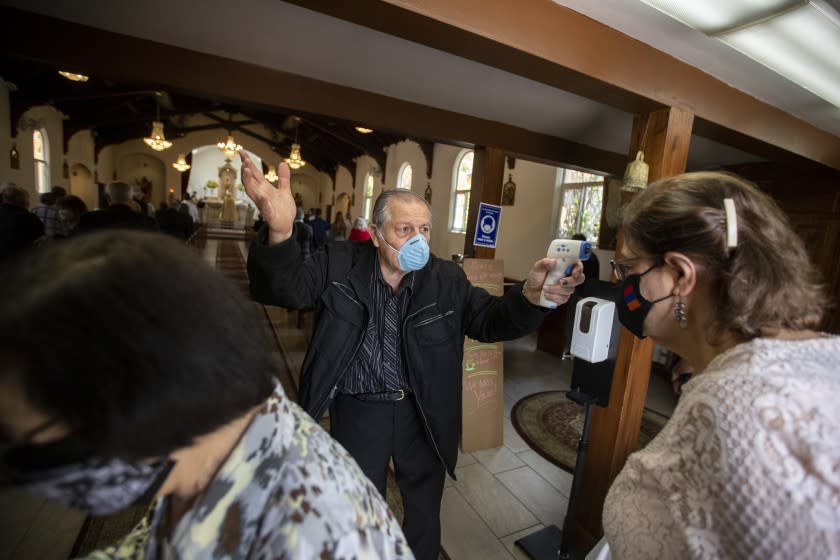 BOYLE HEIGHTS, CA - APRIL 25: Usher Antoine Soumakian takes parishioners temperatures as they file in for Sunday service at Our Lady Queen of Martyrs Church, an Armenian church on Sunday, April 25, 2021 in Boyle Heights, CA. (Brian van der Brug / Los Angeles Times)