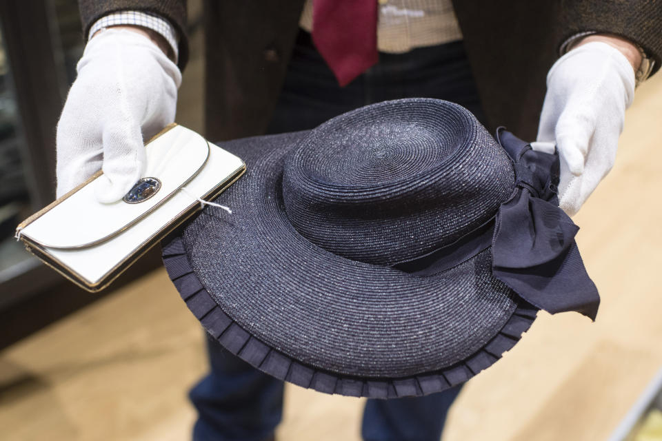 An empolyee holds a wallet and a strawhat that belonged to Eva Braun the wife of Adolf Hitler prior to an auction in Grasbrunn, Germany, Wednesday, Nov. 20, 2019. A Jewish group has sharply condemned an auction of Nazi memorabilia in Germany. The European Jewish Association condemned the auction Wednesday at Hermann Historica in Munich, saying that “it’s wrong to make money off these blood-soaked items, especially in Germany of all places". (Matthias Balk/dpa via AP)