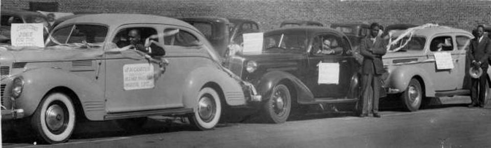 Three cars in a Juneteenth parade in the 1940s, each with a sign advertising a business. The sign on the first car reads “J. H. Goates Assistant Agency Director Universal Life.” A sign on another car reads “Creating jobs for the youth.”