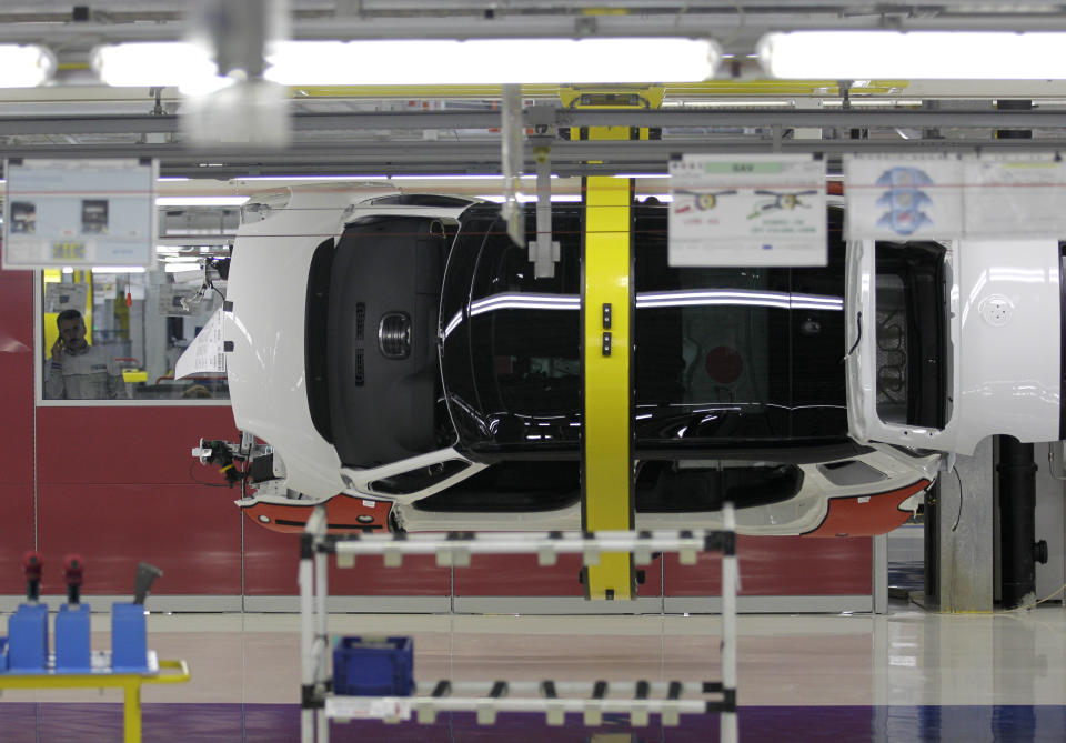 Serbian factory worker look at a Fiat 500 L car in the assembly hall in the new Fiat factory, in Kragujevac, some 100 kilometers (70 miles) south of Belgrade, Serbia, Monday, April 16, 2012. Italian carmaker Fiat has opened a production line in Serbia for its new 500L family model, to expand on the popularity of its two-door 500 city car. Fiat hopes to sell about 160,000 hatchbacks a year produced in this central Serbian town, to take advantage of low wages, tax breaks and government subsidies. (AP Photo/Darko Vojinovic)