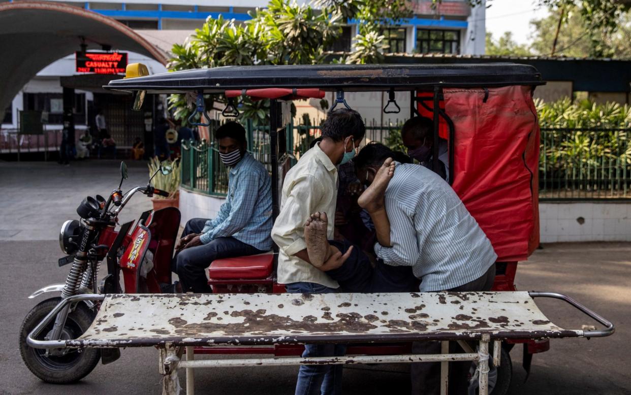 In New Delhi, a man is brought to hospital by his family in a rickshaw