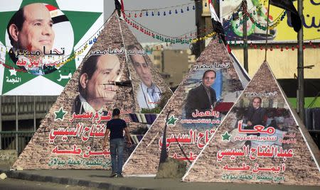 A man walks near replicas of Giza Pyramid covered with banners of presidential candidate and former army chief Abdel Fattah al-Sisi in Cairo May 26, 2014. REUTERS/Amr Abdallah Dalsh