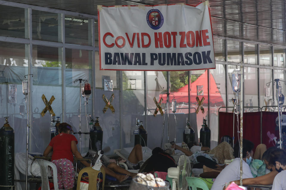 COVID-19 patients stay outside the Amang Rodriguez Memorial Medical Center emergency area as they wait for rooms to be vacated in Marikina, Philippines on Friday March 26, 2021. The Department of Health reported over 9,800 new COVID-19 cases today, the highest number since the pandemic hit the country last year as it struggles to contain an alarming surge in coronavirus infections. Sign reads "COVID Hot Zone, Do Not Enter." (AP Photo/Aaron Favila)