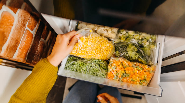 Hand pulling bag of frozen corn from freezer