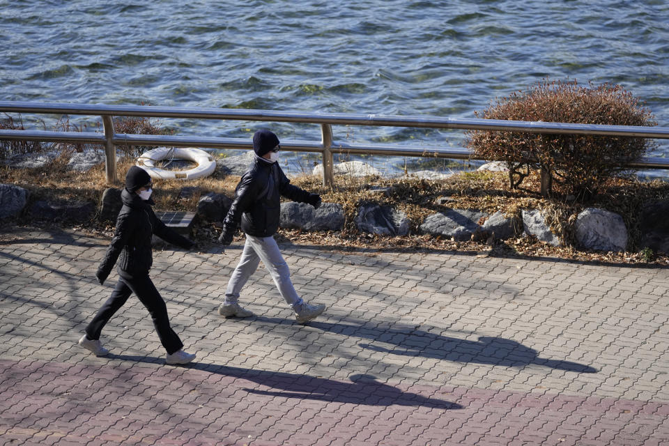 Visitors wearing face masks as a precaution against the coronavirus, walk at a park in Goyang, South Korea, Saturday, Dec. 4, 2021. South Korea again broke its daily records for coronavirus infections and deaths and confirmed three more cases of the new omicron variant as officials scramble to tighten social distancing and border controls. (AP Photo/Lee Jin-man)