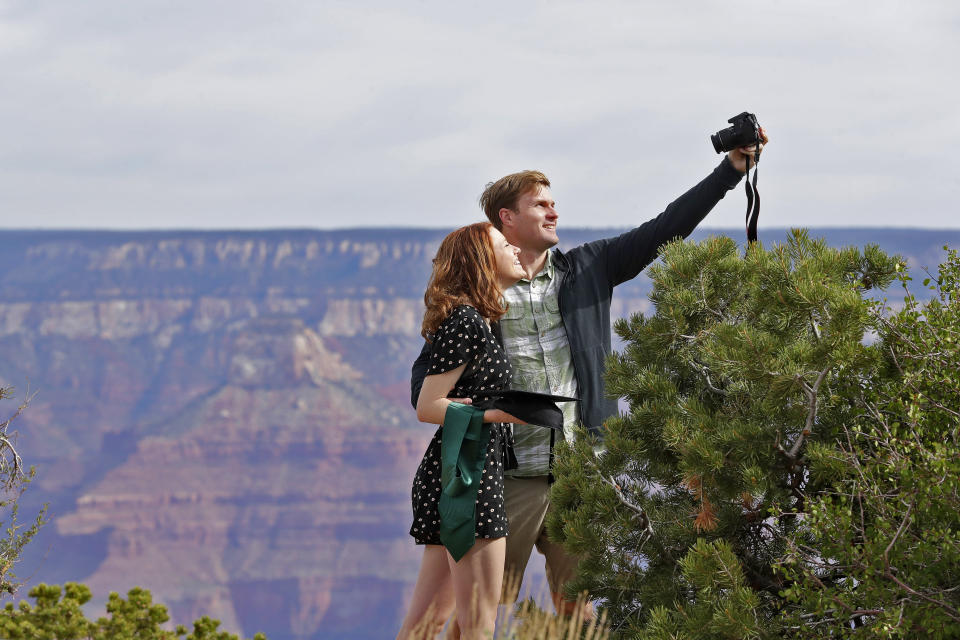 Recent Baylor University graduate Cady Malachowski takes a photo with Andrew Fink at the Grand Canyon Friday, May 15, 2020, in Grand Canyon, Ariz. Tourists are once again roaming portions of Grand Canyon National Park when it partially reopened Friday morning, despite objections that the action could exacerbate the coronavirus pandemic.. (AP Photo/Matt York)