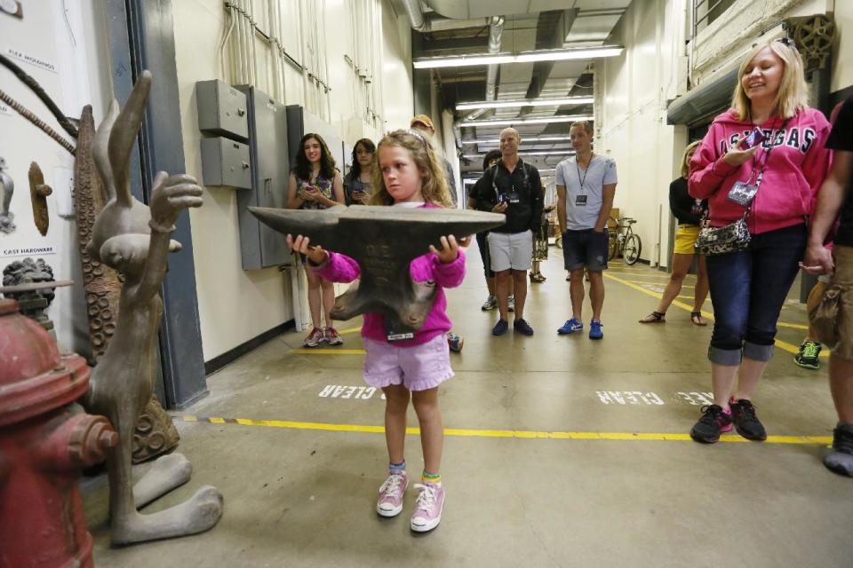 This photo taken Wednesday, June 5, 2013 shows tourist Lisa Halloran, 8, holding a foam prop anvil from "The Coyote and The Road Runner" cartoons series on the VIP Experience at Universal Studios Hollywood in Los Angeles. Many theme parks now have VIP tours with perks usually reserved for celebrities _ private tour guides, no waits for the biggest attractions, reserved seating at shows and parades along with behind-the-scenes peaks at places normally off limits. (AP Photo/Damian Dovarganes)