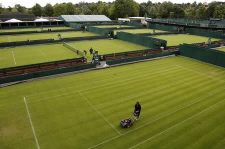 A grounds keeper mows an outside court a day before the start of the Wimbledon Tennis Championships in London June 23, 2013. REUTERS/Chris Helgren