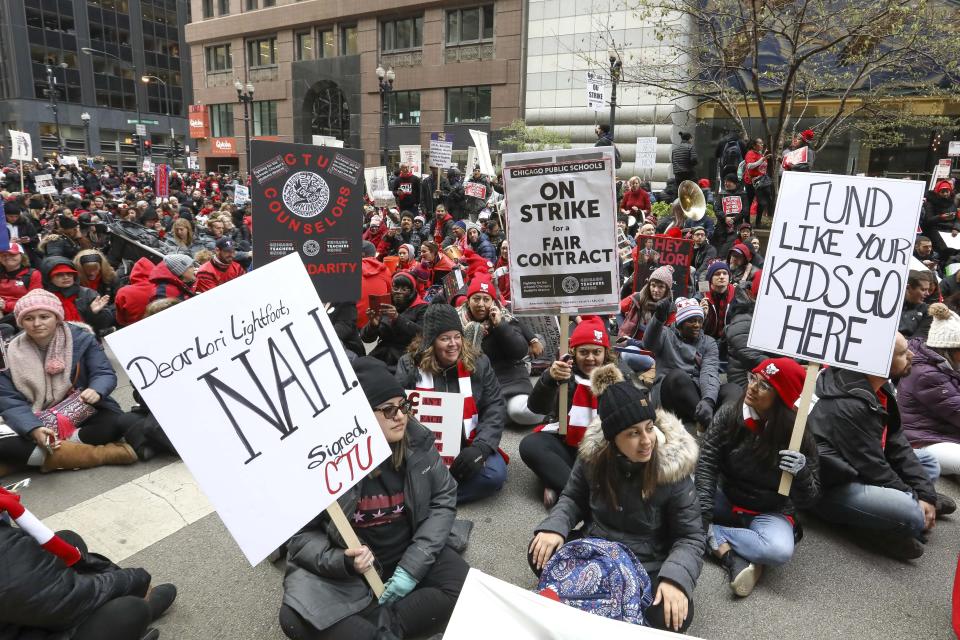 Striking Chicago teachers sit on La Salle Street outside City Hall on the fifth day of canceled classes Wednesday, Oct. 23, 2019, in Chicago. The protest was timed to coincide with Mayor Lori Lightfoot's first budget address. (AP Photo/Teresa Crawford)