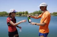 Jacky Hunt-Broersma, left, gets a delivery of champagne from her husband, Edwin Broersma, after Jacky finished her 102nd marathon in 102 days, this one at Veterans Oasis Park, Thursday, April 28, 2022, in Chandler, Ariz. (AP Photo/Ross D. Franklin)