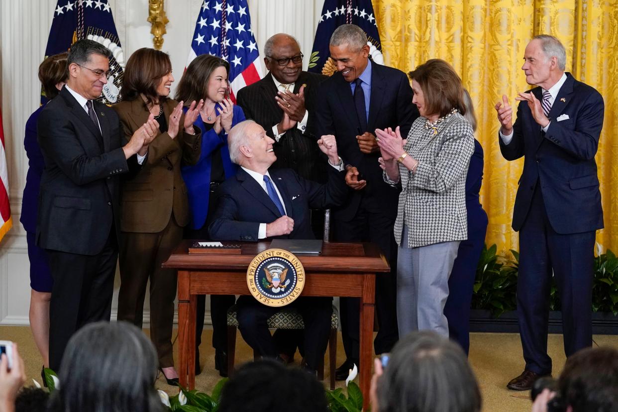 President Joe Biden looks to former President Barack Obama after signing an executive order during an event about the Affordable Care Act in the East Room of the White House in Washington on Tuesday, April 5, 2022. Also seen are Health and Human Services Secretary Xavier Becerra, Vice President Kamala Harris, Rep. Angie Craig, D-Minn., House Majority Whip James Clyburn, D-S.C., House Speaker Nancy Pelosi of Calif. and Sen. Tom Carper, D-Del.