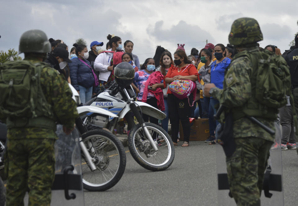 The relatives of prisoners gather outside Turi jail where soldiers stand guard after an inmate riot broke out in Cuenca, Ecuador, Tuesday, Feb. 23, 2021. Deadly riots broke out in prisons in three cities across the country due to fights between rival gangs, according to police. (Boris Romoleroux/API via AP)