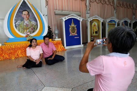 Well-wishers wear pink shirts as they pose for a photograph in front of a picture of Thailand's King Bhumibol Adulyadej at Siriraj Hospital in Bangkok, Thailand, October 11, 2016. REUTERS/Chaiwat Subprasom