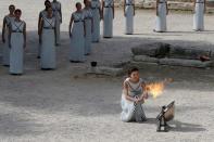 Olympics - Dress Rehearsal - Lighting Ceremony of the Olympic Flame Pyeongchang 2018 - Ancient Olympia, Olympia, Greece - October 23, 2017 Greek actress Katerina Lehou, playing the role of High Priestess, lights a torch from the sun's rays reflected in a parabolic mirror during the dress rehearsal for the Olympic flame lighting ceremony for the Pyeongchang 2018 Winter Olympic Games at the site of ancient Olympia in Greece REUTERS/Costas Baltas