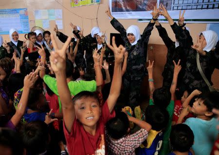 Government female soldiers wearing white hijabs and child evacuees make peace signs as part of their psychosocial activities at one of the evacuation centres in Balo-i town, Lanao Del Norte, southern Philippines, September 8, 2017. REUTERS/Romeo Ranoco