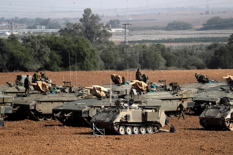 Israeli soldiers stand atop armoured personnel carriers in a staging area near the border with Gaza, in southern Israel