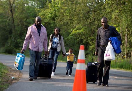 A family that said they are from Haiti walks to the US-Canada border from Roxham Road in Champlain, New York, U.S. August 11, 2017. REUTERS/Christinne Muschi