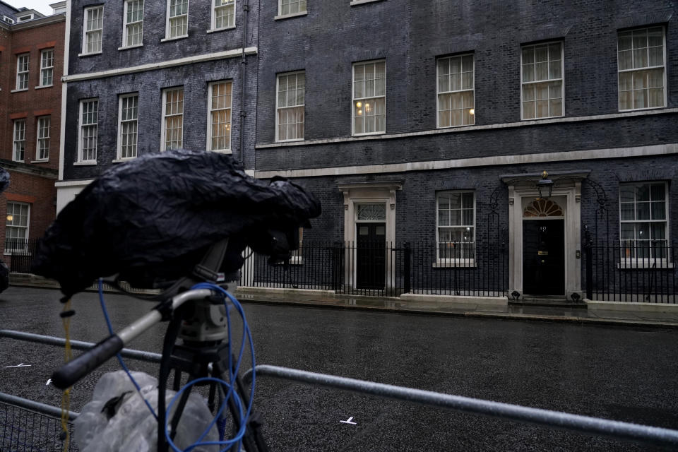 A television camera covered from the rain points towards the front door of 10 Downing Street, in London, Friday, Feb. 4, 2022. Four of Boris Johnson's most senior staff quit on Thursday, with a fifth staff member resigning on Friday morning, triggering new turmoil for the embattled British prime minister. Johnson's grip on power has been shaken by revelations that his staff held "bring your own booze" office parties, birthday celebrations and "wine time Fridays" in 2020 and 2021 while millions in Britain were barred from meeting with friends and family during coronavirus lockdowns. (AP Photo/Alberto Pezzali)