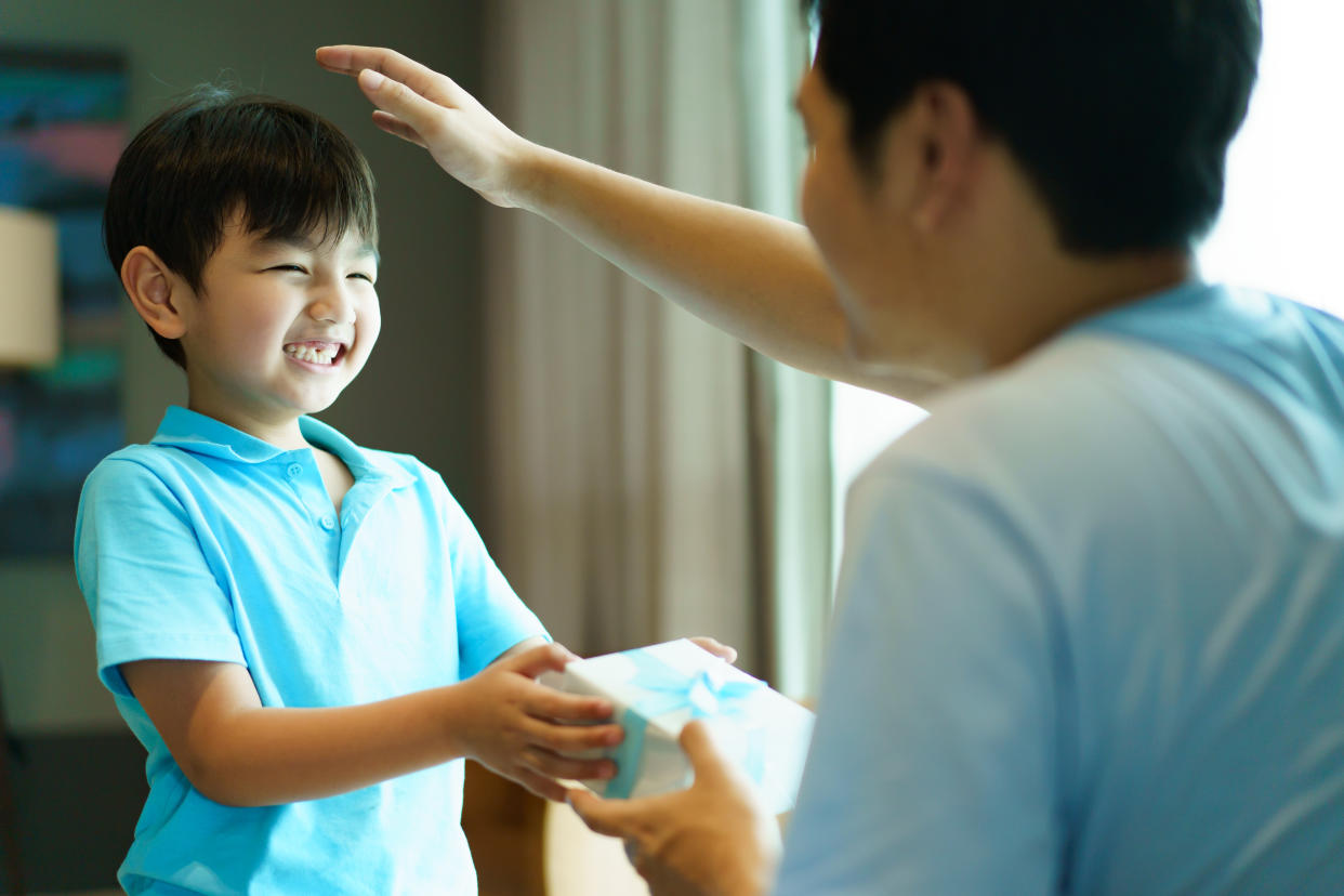 Lovely Asian little young boy giving his dad a gift for the international father's day. Little boy give his father a gift.