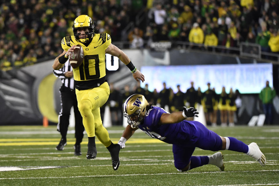 Oregon quarterback Bo Nix (10) eludes a tackle by Washington defensive lineman Voi Tunuufi (90) during the first half of an NCAA college football game Saturday, Nov. 12, 2022, in Eugene, Ore. (AP Photo/Andy Nelson)