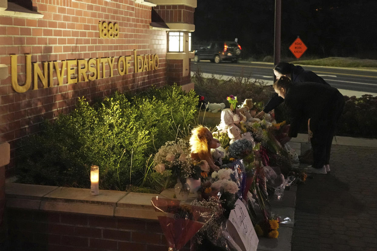 Two people place flowers at a growing memorial in front of a campus entrance sign for the University of Idaho, Wednesday, Nov. 16, 2022, in Moscow, Idaho. Four University of Idaho students were found dead on Sunday, Nov. 13, 2022, at a residence near campus. (AP Photo/Ted S. Warren)