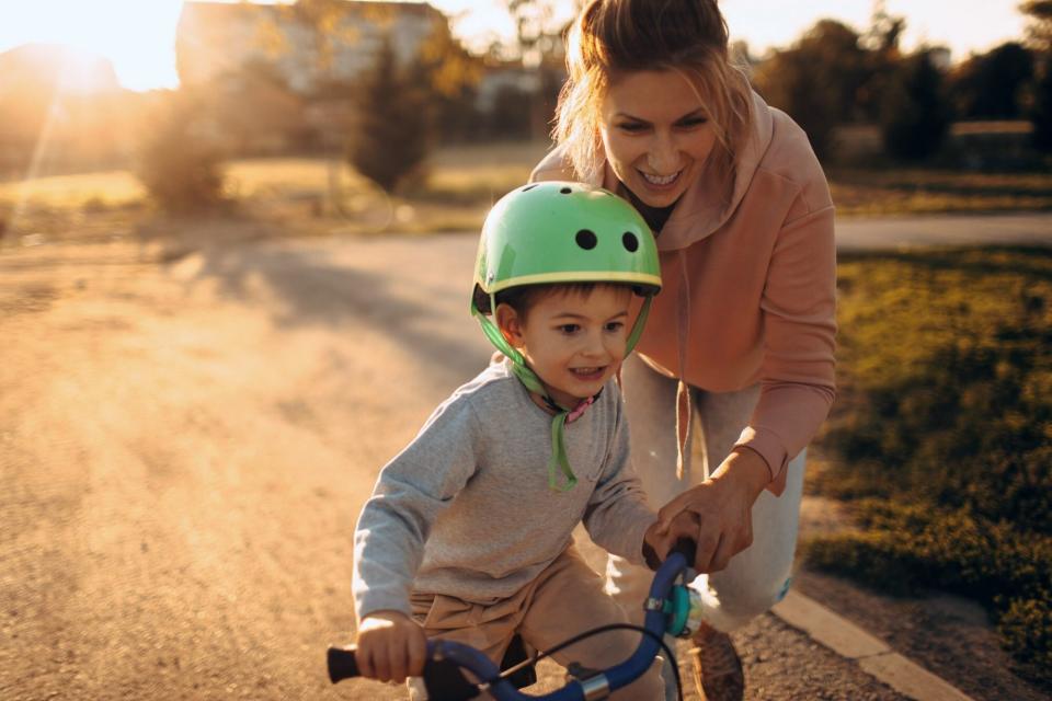 An image of a mom teaching her son to ride a bike.
