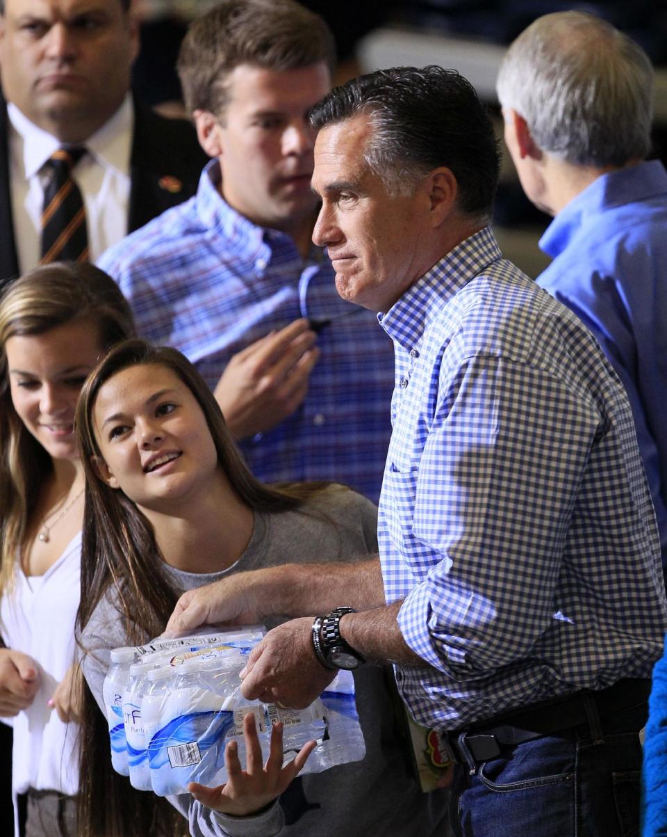 Republican presidential candidate, former Massachusetts Gov. Mitt Romney hands a pack of bottled water to a student as he helped collect donations at a storm relief event, Tuesday, Oct. 30, 2012, at James S. Trent Arena in Kettering, Ohio. (AP Photo/Al Behrman)