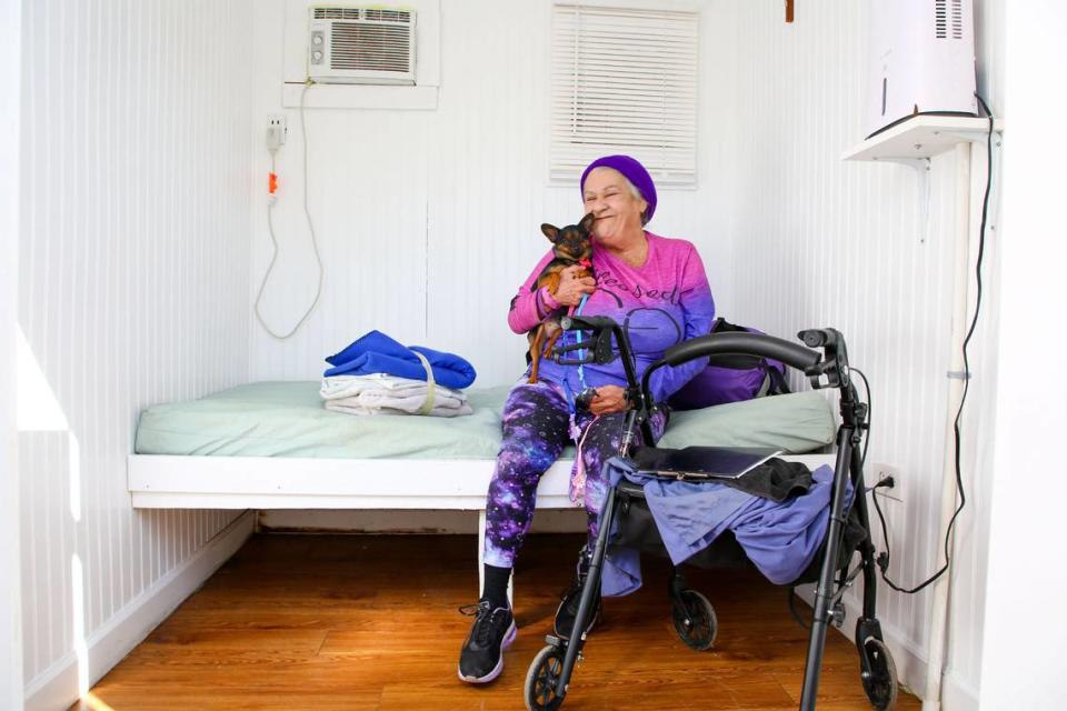 La nueva habitante de Pinellas Hope Sandy Silvey visita a su chihuahua Bay Bay en su Hope Cottage, el martes 27 de febrero de 2024, en Clearwater. Las Hope Cottages son contenedores de acero de 20 pies que se han reconfigurado para crear tres habitaciones en las que viven los habitantes y que sustituyen a las tiendas de campaña.