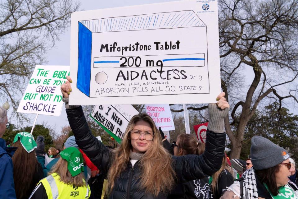 Abortion-rights activists holds a signs as they protest outside of the Supreme Court during a rally, March 26, 2024 (AP)